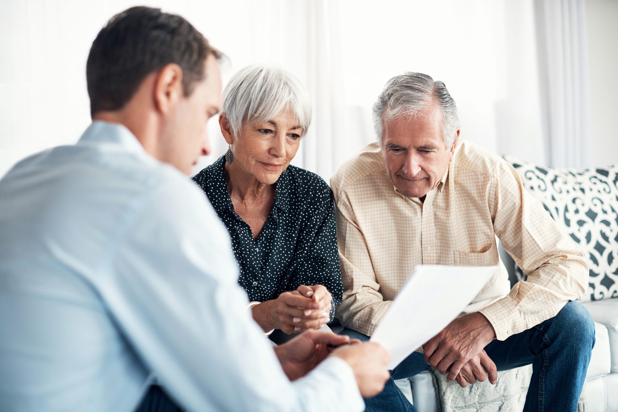 Three people reviewing documents together on sofa.