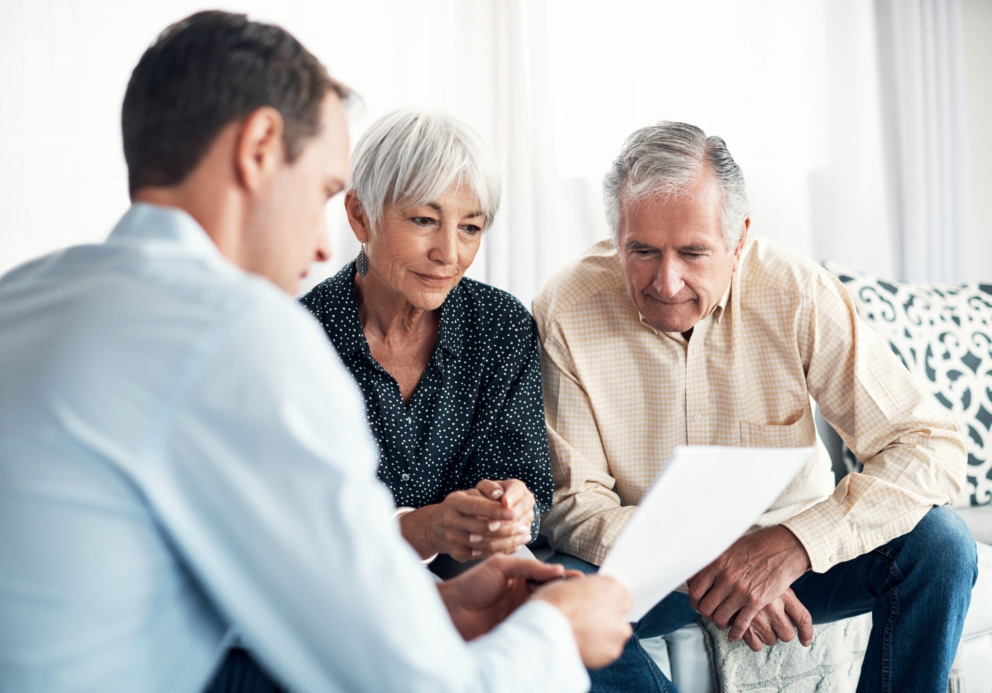 Three people reviewing documents together on sofa.